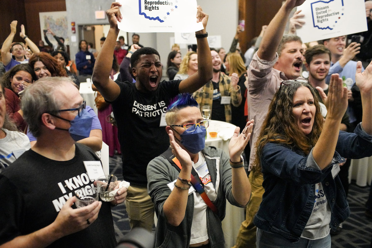 Abortion rights activists cheering and holding signs at an election watch event.