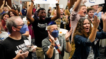 Abortion rights activists cheering and holding signs at an election watch event.