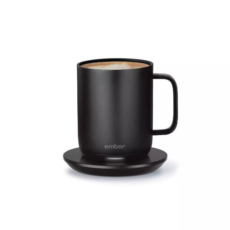 A Black satin sheen mug on a black coaster. Coffee is just visible at the top of the mug.