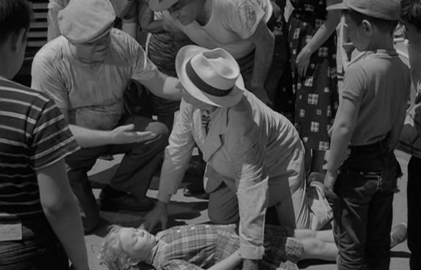 A crowd of people over an unconscious young girl on the ground in the Twilight Zone episode One For the Angels