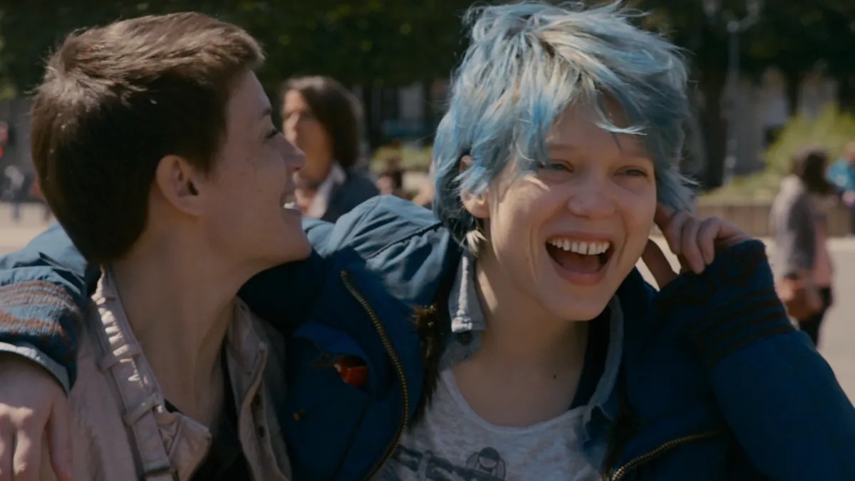 Two young women laugh with their arms around eachother in "Blue is the warmest colour" 