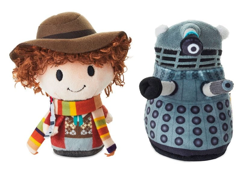 Plushies in a chibi style of the Fourth Doctor and a grey-blue Dalek. The Doctor has brown curls, a hat, and a long rainbow scarf.