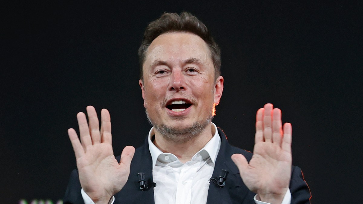 Elon Musk speaking, his hands in the air