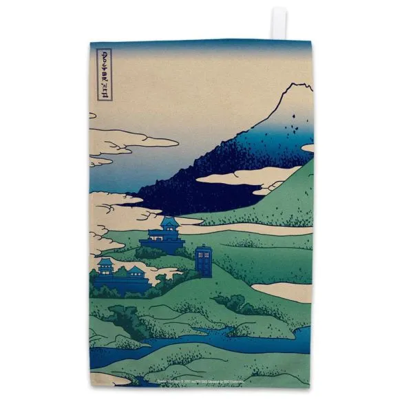 A tea towel with a Japanese style print of a mountain The Tardis, a rectangular blue bod with windows, appears halfway into the image.