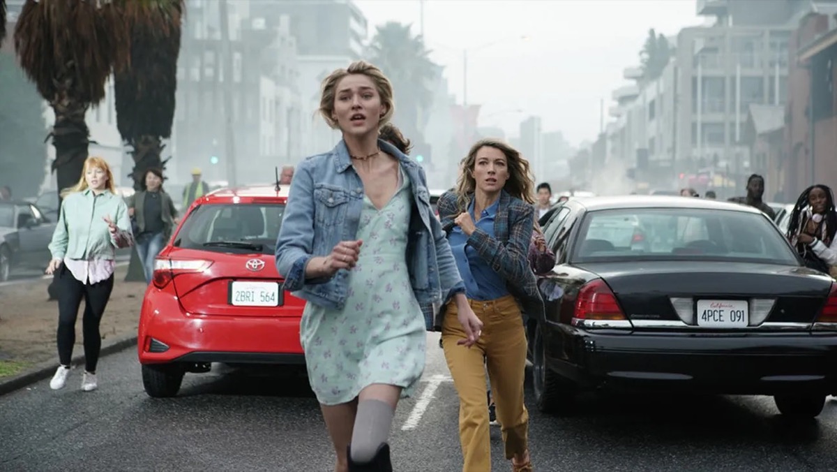 A young woman and a teenager run through chaos in the streets in "La Brea"
