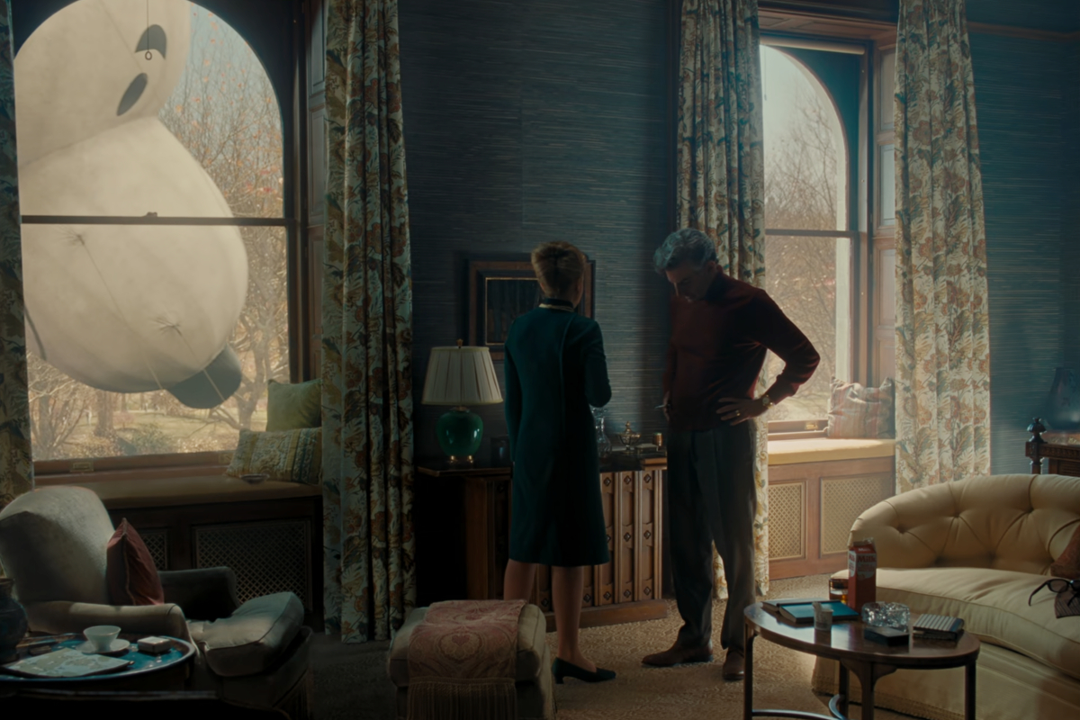 A large Snoopy parade float hovers in a window as Felicia (Carey Mulligan) and Leonard Bernstein (Bradley Cooper) argue in 'Maestro'