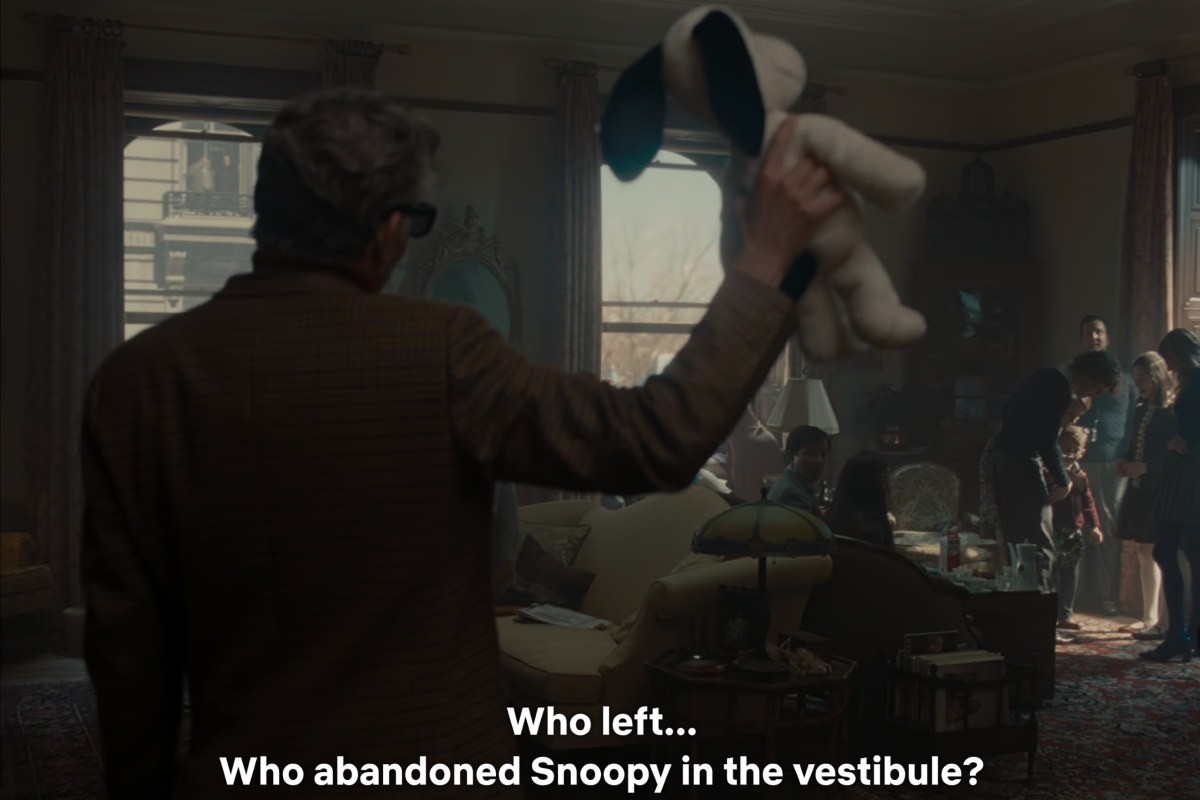 Leonard Bernstein (Bradley Cooper) holds a stuffed Snoopy toy and questions his family in 'Maestro.' The caption reads: "Who left... Who abandoned Snoopy in the vestibule?"
