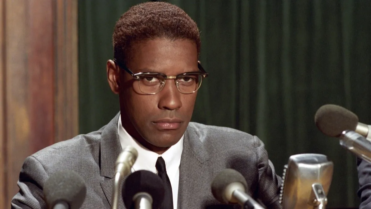 Denzel Washington as Malcolm X staring out over microphones at a press conference in "Malcolm X"