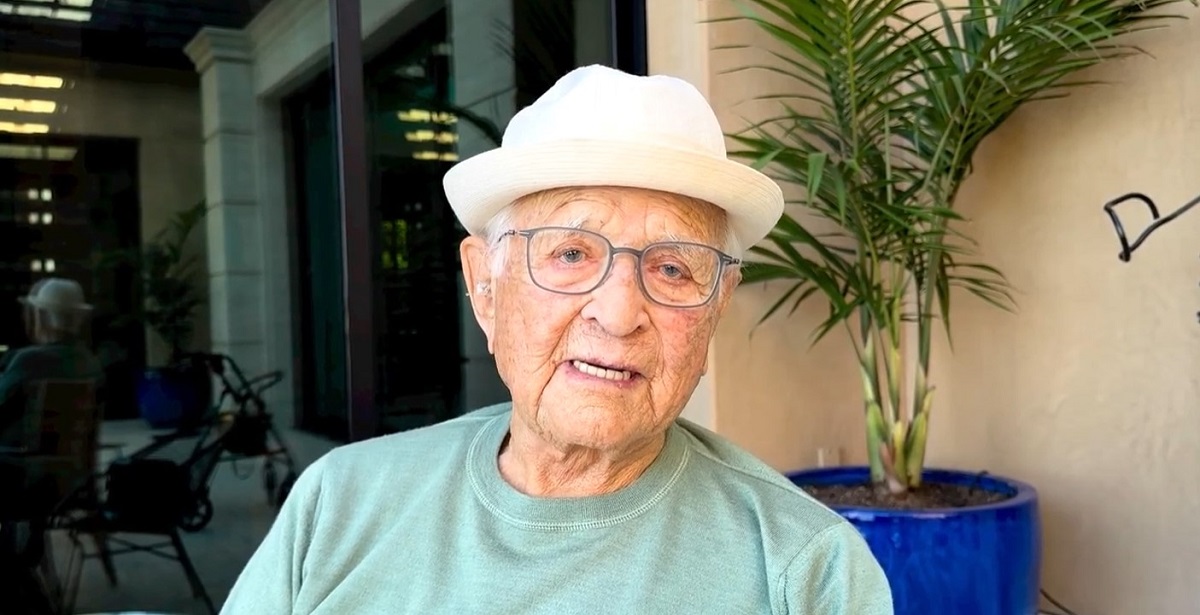 Screencap of Norman Lear. He is a white Jewish 101 year old man wearing a light green sweatshirt, glasses, and a white porkpie hat. He's looking into the camera as he speaks.