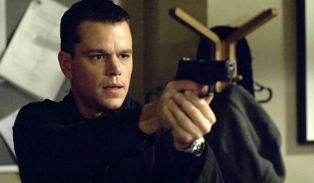 Matt Damon as Jason Bourne holding and pointing a gun in The Bourne Ultimatum