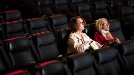 Two women sit in an empty movie theater