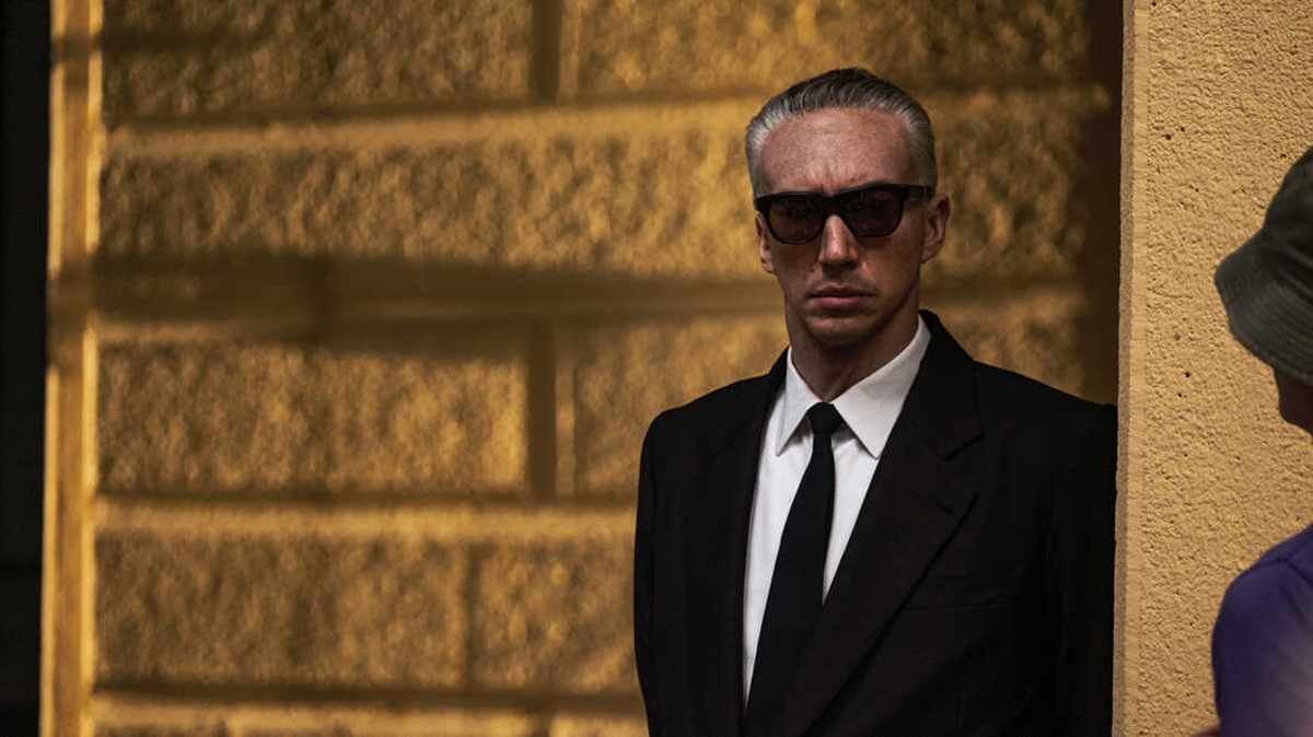 Enzo Ferrari standing against a wall in Ferrari