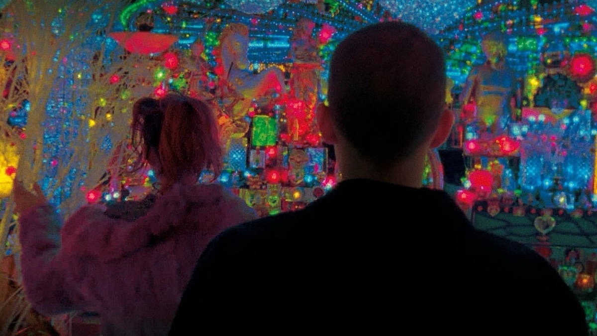Two young people stand in front of techincolor lights in "Enter the Void" 