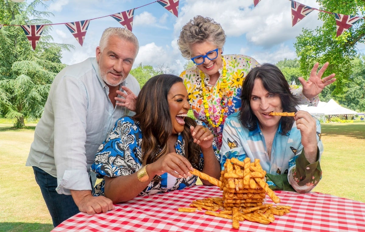 The judges and cohosts of 'The Great British Baking Show' laugh together over foood