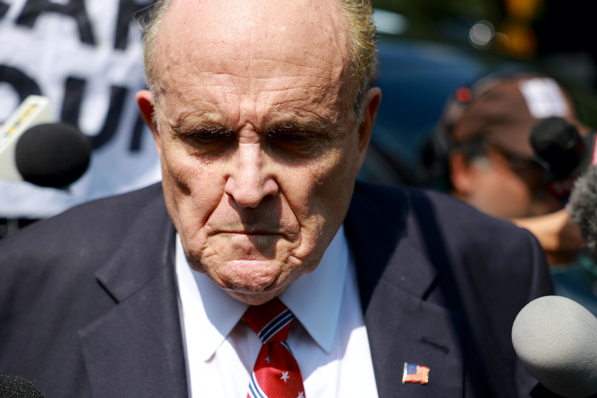 Rudy Giuliani looks sad in a crowd of reporters