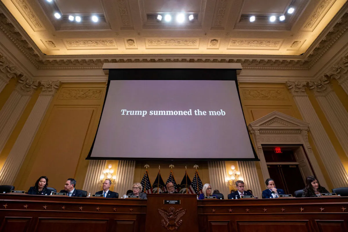 The House Select Committee to Investigate the January 6th Attack on the US Capitol sits with the words "Trump summoned the mob" projected on a giant screen behind them.