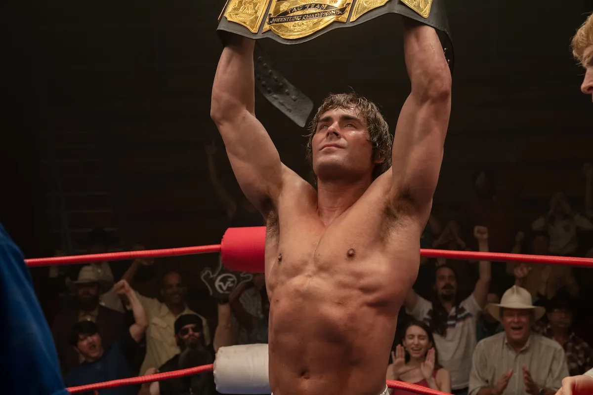 Zac Efron holding up the belt in the Iron Claw