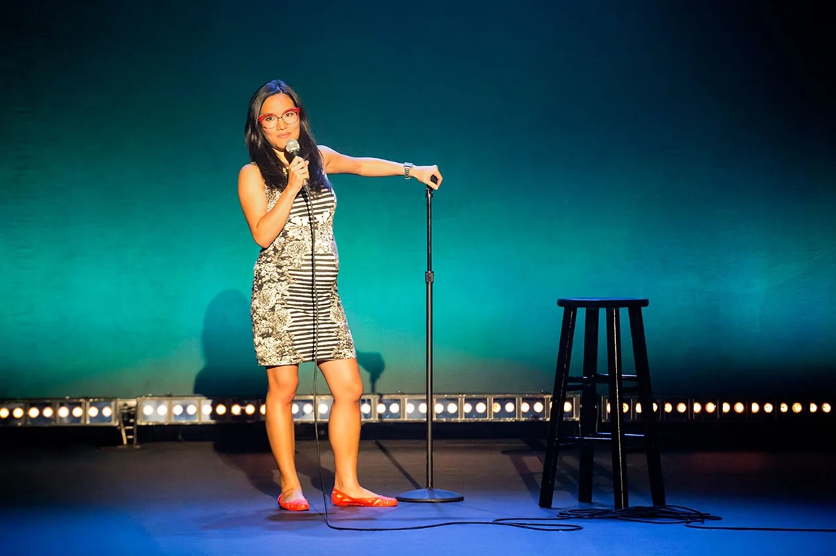 Pregnant comedian Ali Wong wearing a tight leopard print dress on stage during taping of her Hard Knock Wife special