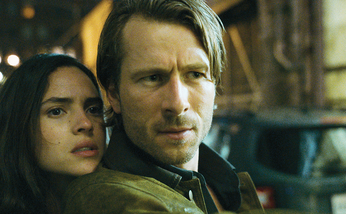 Glen Powell and Adria Arjona standing very close together in 'Hit Man'