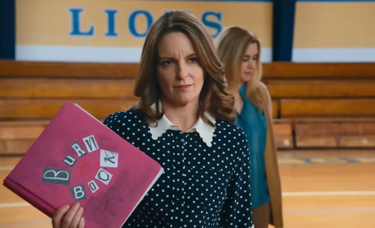 Ms Norbury (Tina Fey) holds up a pink Burn Book with exasperated look on her face