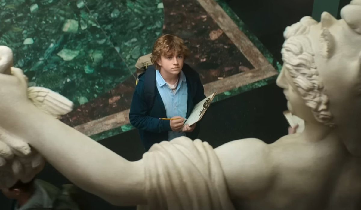 Percy Jackson stands in front of a statue of Perseus, the Greek hero he's named after