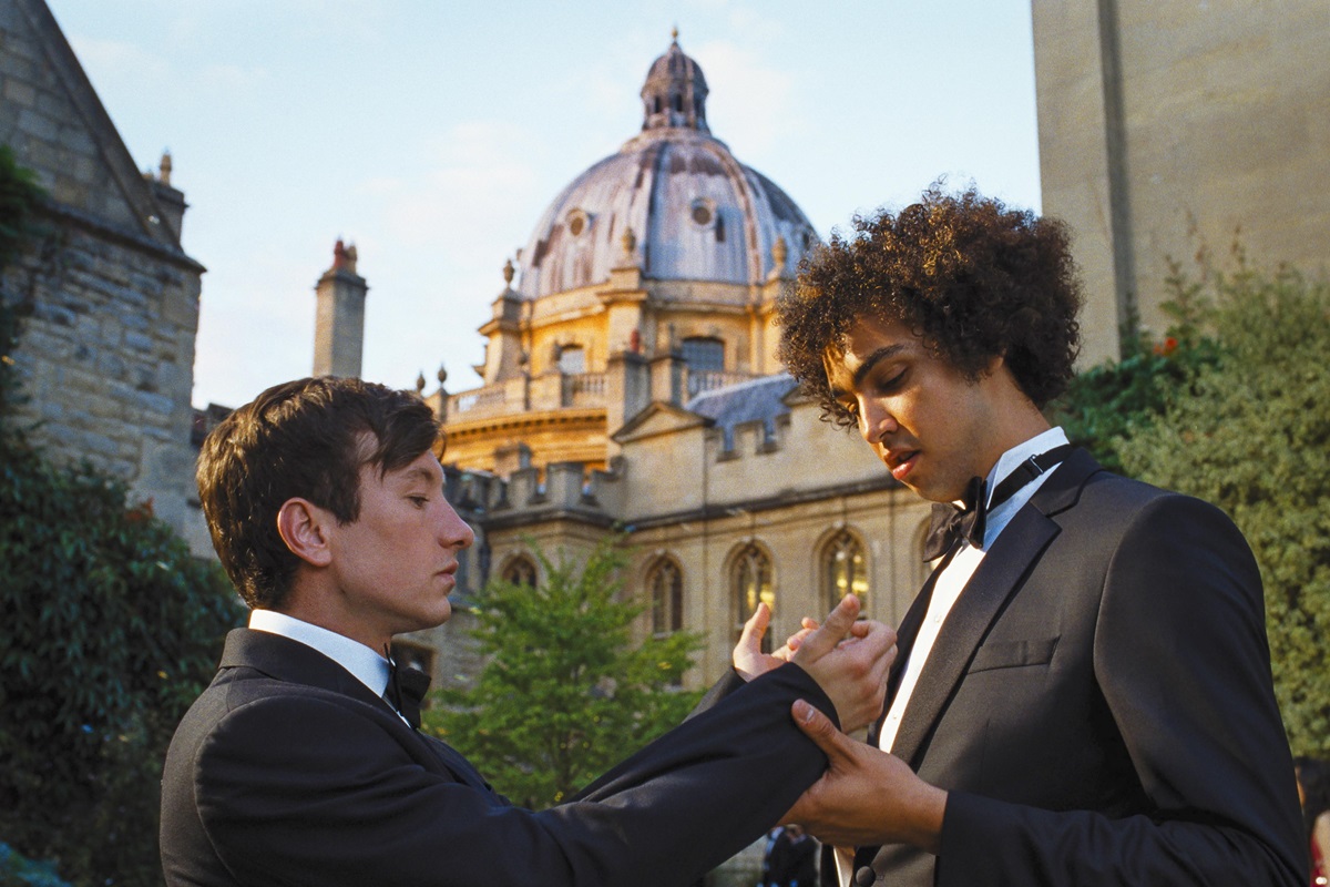 Farleigh (Archie Madekwe ) examines Oliver's (Barry Keoghan) cuffs in Saltburn