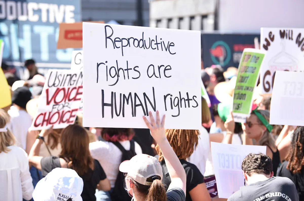 A group of protesters with one holding a sign reading "Reproductive rights are human rights"