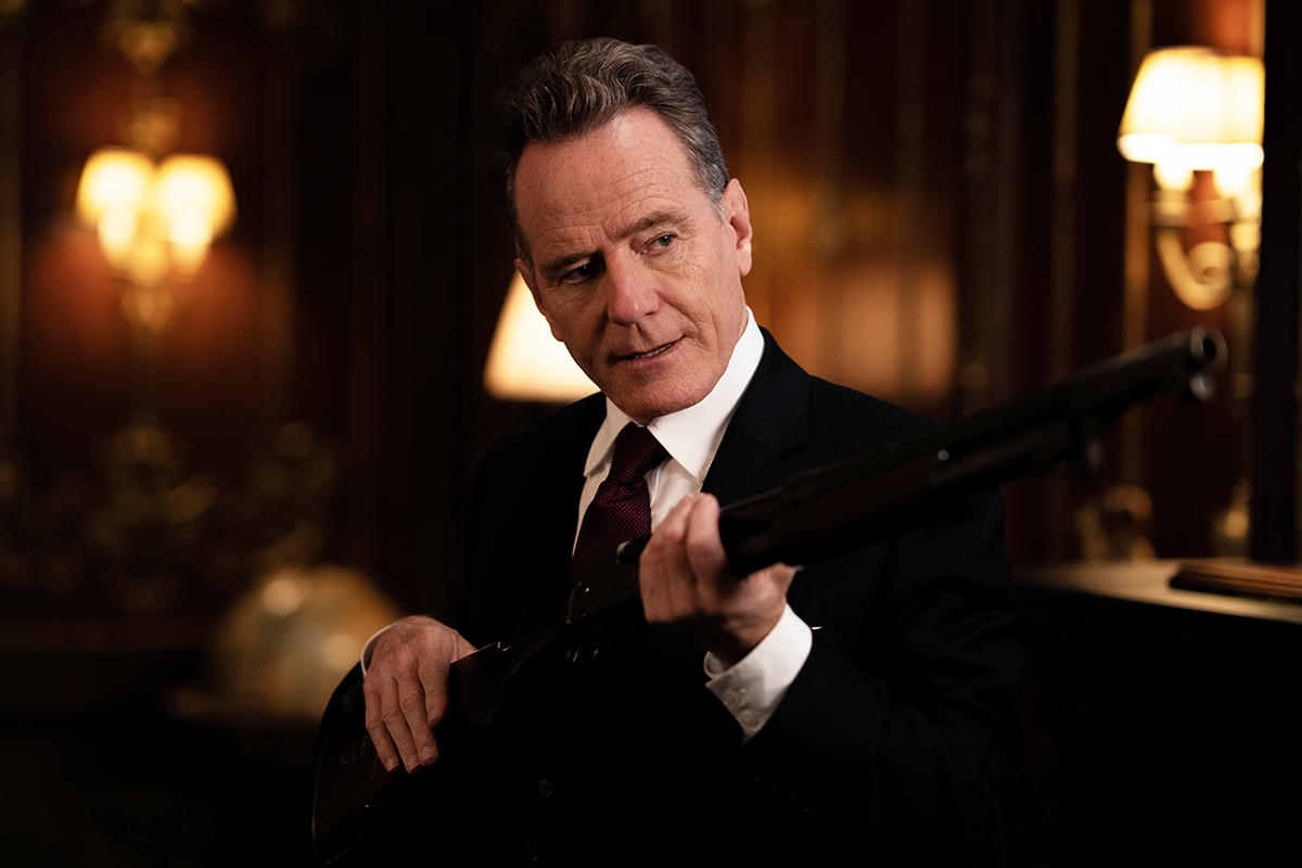 Bryan Cranston holding a gun and standing in Argylle