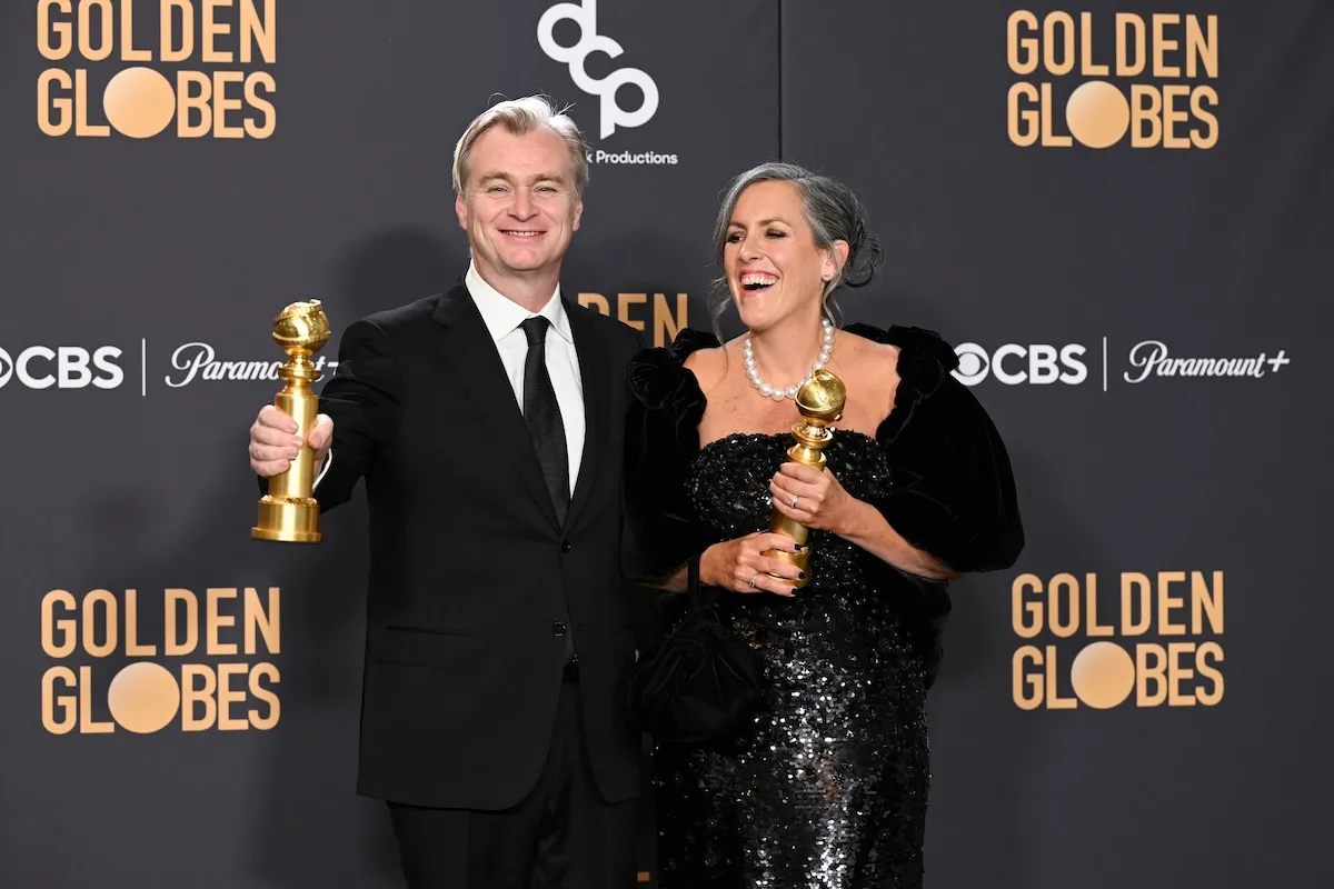 Christopher Nolan and Emma Thomas standing with their Golden Globes