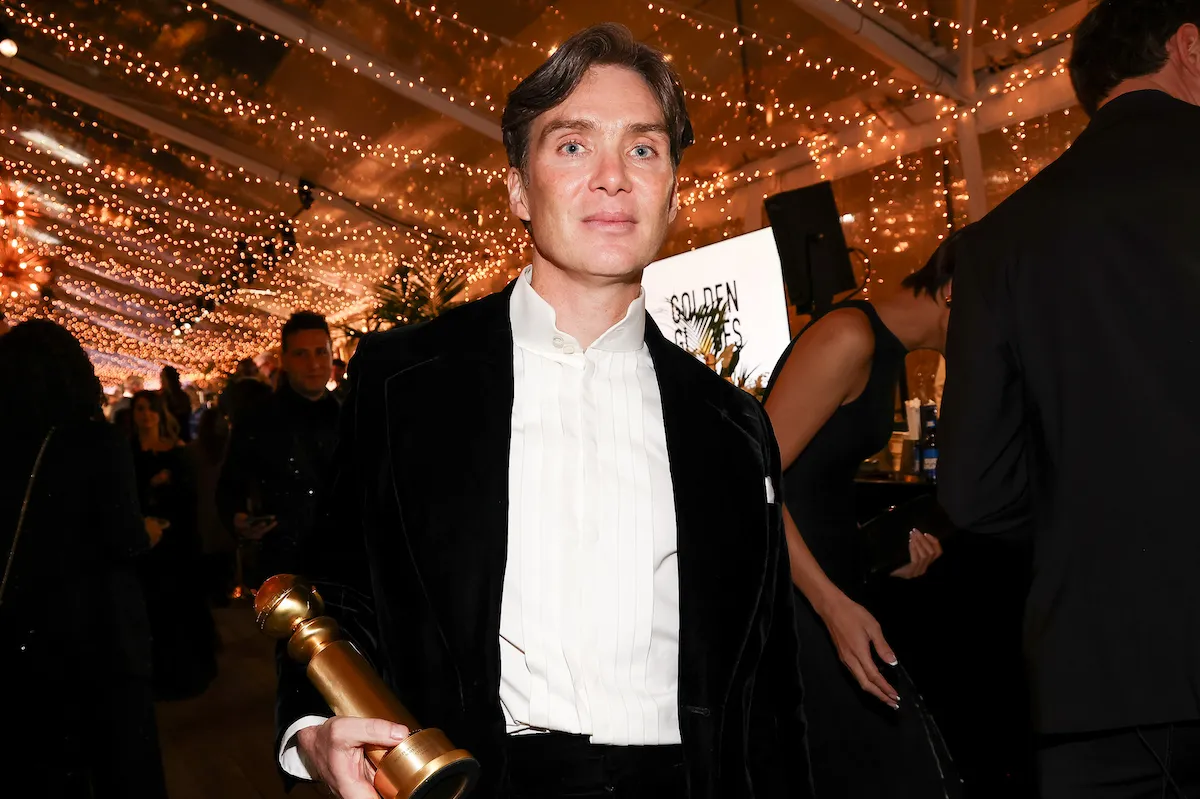Cillian Murphy holds his Golden Globe statue looking uncomfortable in a crowd.