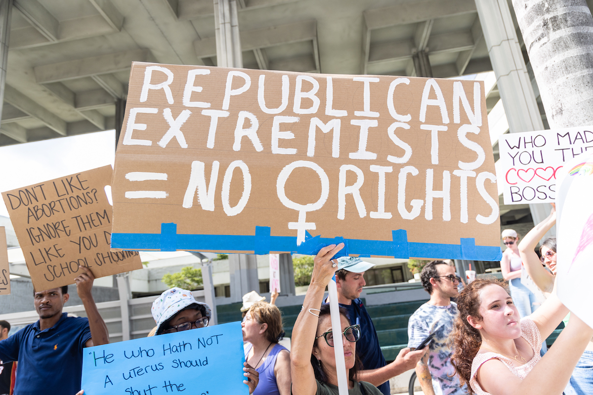 Abortion rights protesters, one holding a large sign reading "Republican extremists = No [woman symbol] rights"