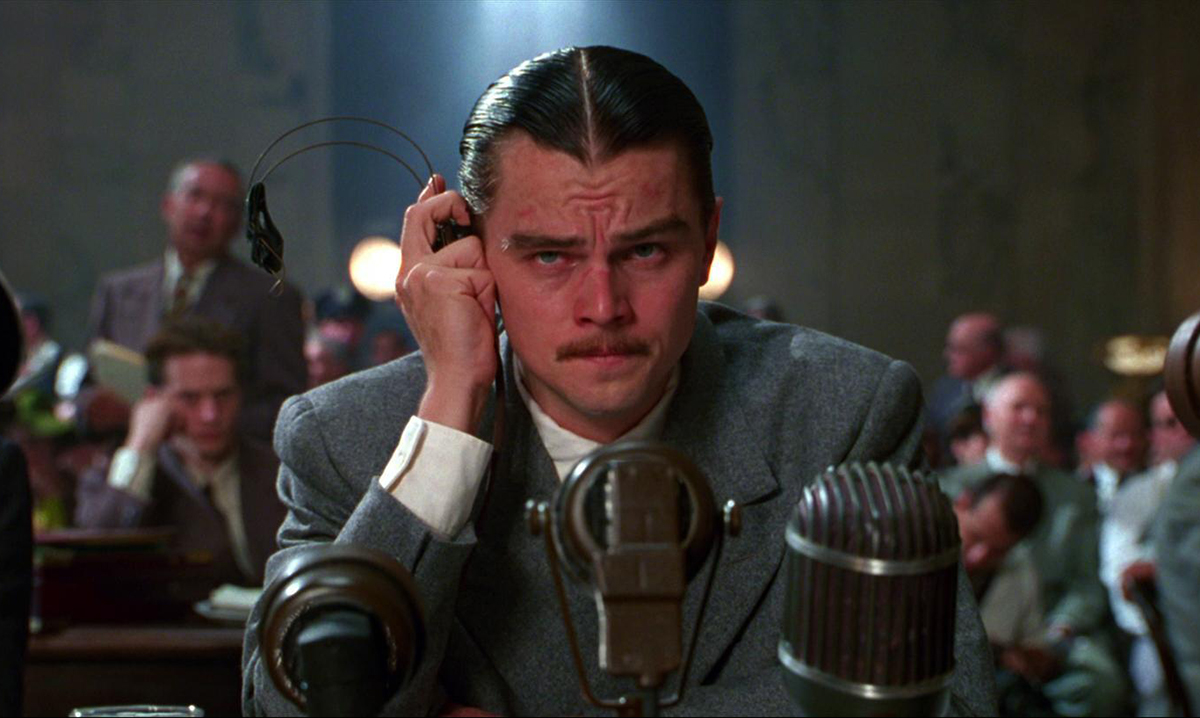 Leonardo DiCaprio holding headphones to his ear in the Aviator