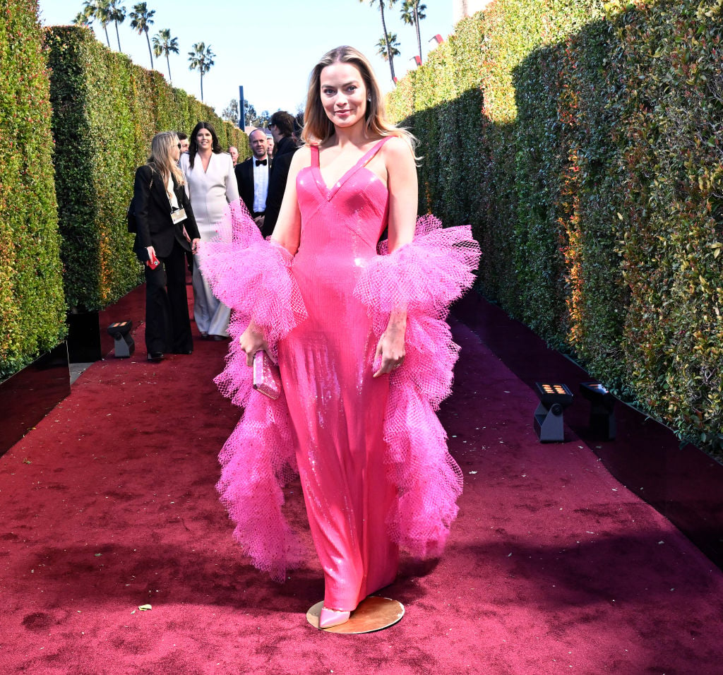 Margot Robbie on the Golden Globes red carpet in a hot pink gown and matching tulle boa.