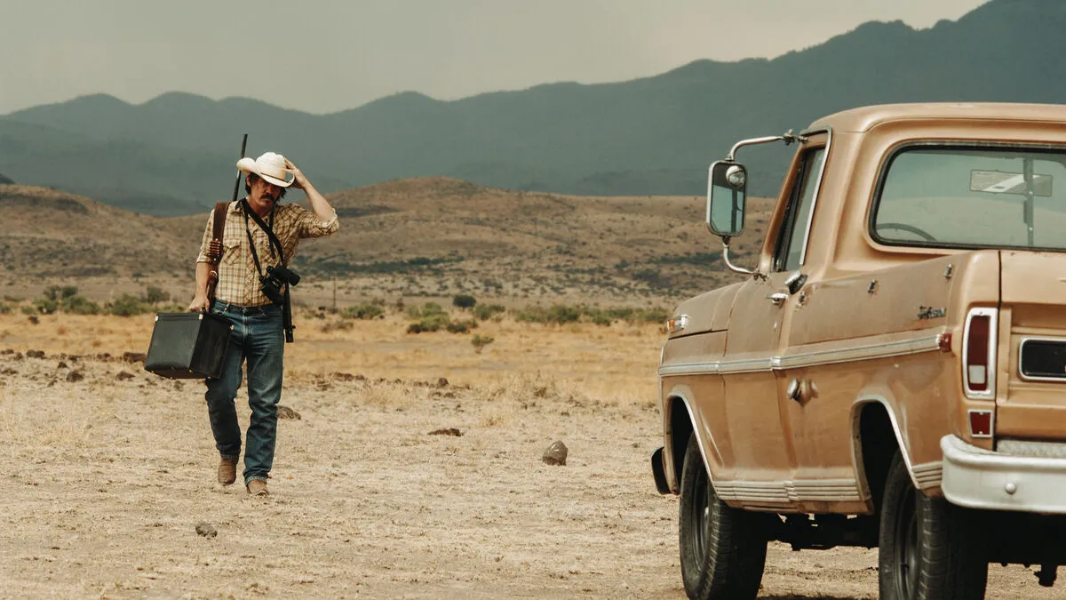 A man in a cowboy hat walks through the desert towards his car in "No Country For Old Men" 