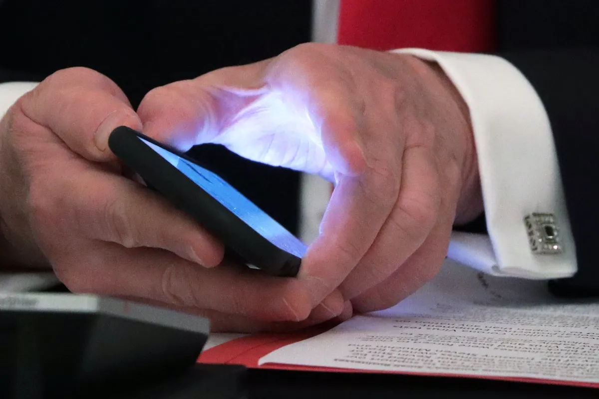 A closeup of Donald Trump's hands holding a cell phone.
