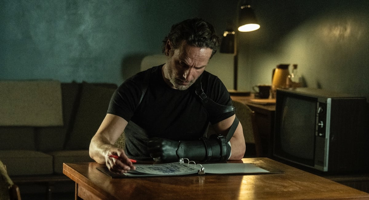 Andrew Lincoln as Rick Grimes, sits at a desk with a prosthetic hand.