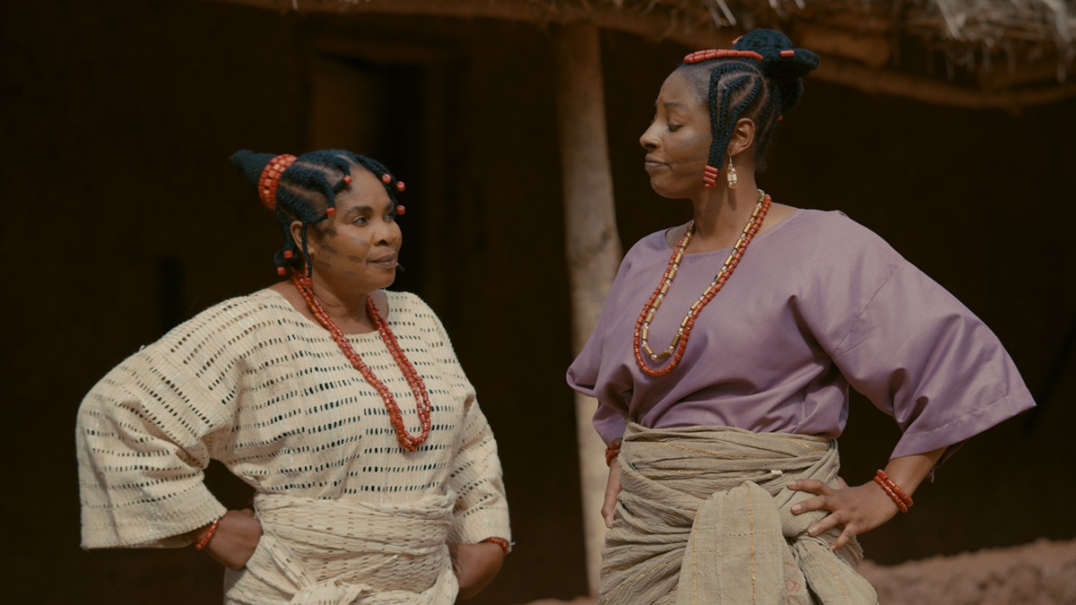 Two African women stand with hands on hips looking at each other
