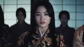 Anna Sawai as Lady Mariko in a scene from 'Shogun.' She is a Japanese woman with long, black hair wearing an ornate floral robe from Feudal Japan. Other Japanese women stand behind her and flanking her.