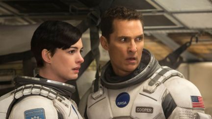 Anne Hathaway as Amelia and Matthew McConaughey as Joseph in a scene from 'Interstellar.' Amelia is a white woman with short, black hair. Joseph is a white man with short dark hair. They are both wearing NASA astronaut suits with their helmets off as they look at something off camera.