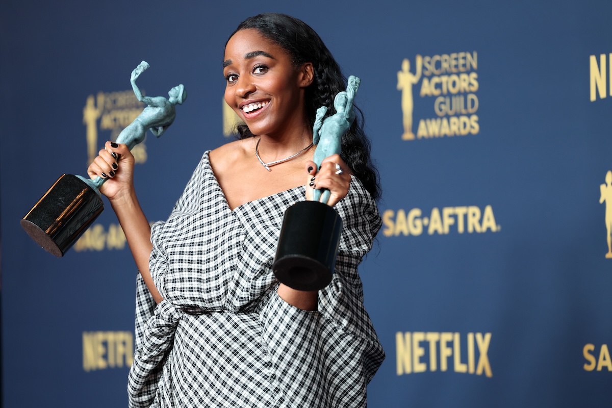 Ayo Edebiri holding up her two SAG awards and smiling at the camera