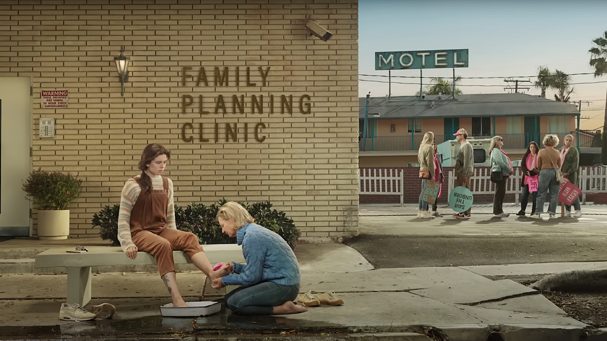 A woman washes the feet of a pregnant woman in front of a "Family Planning Clinic" in a new ad from He Gets Us, the Christian propaganda group that receives funding from ultra-conservative bigots
