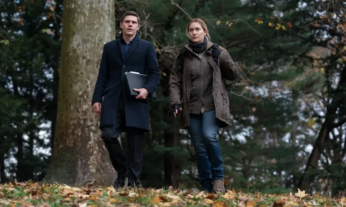a male and female detective walk through the woods together