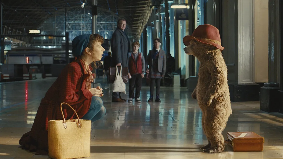 Mary (Sally Hawkins) crouches to say hello to Paddington in the train station as her family looks on