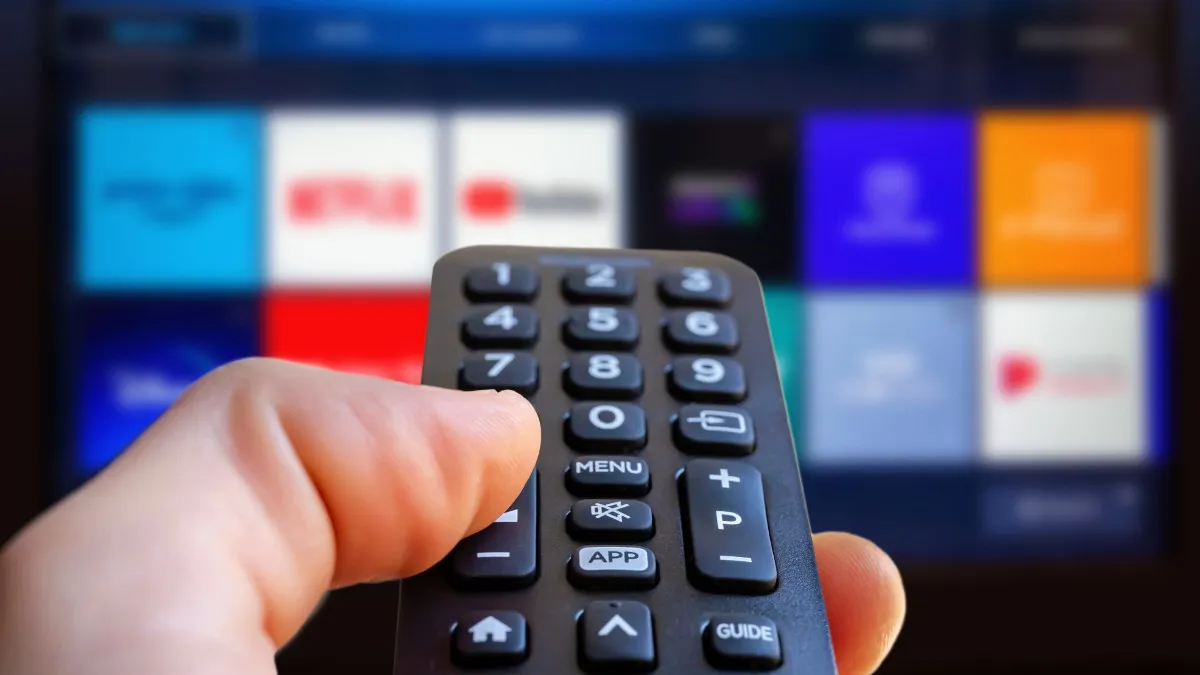 A remote control in front of a TV with streaming apps on the screen