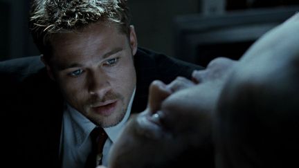 Brad Pitt leans in to look closely at a corpse in Se7en