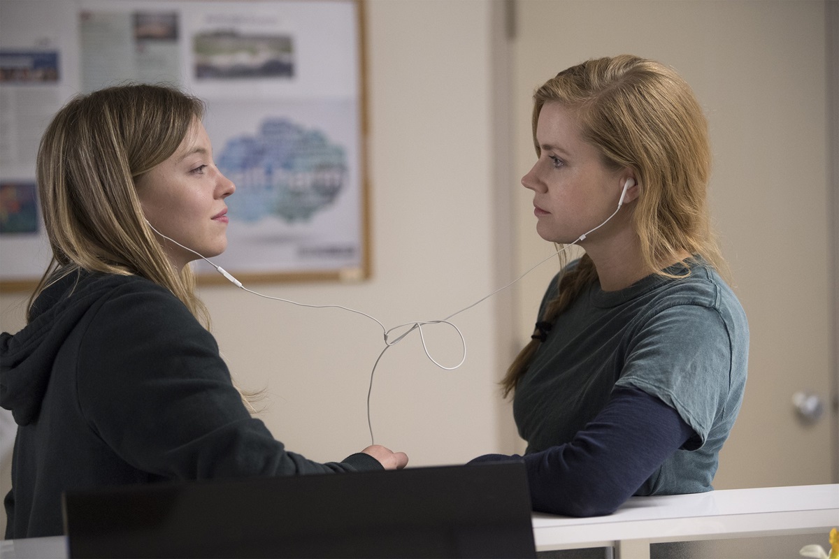 Sydney Sweeney and Amy Adams gaze at each other and share ear buds in Sharp Objects