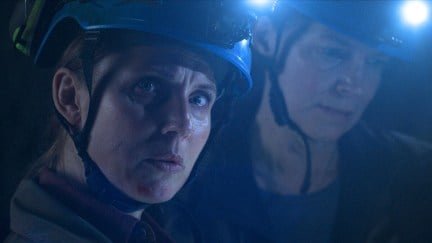 A woman and man in mining helmets look concerned