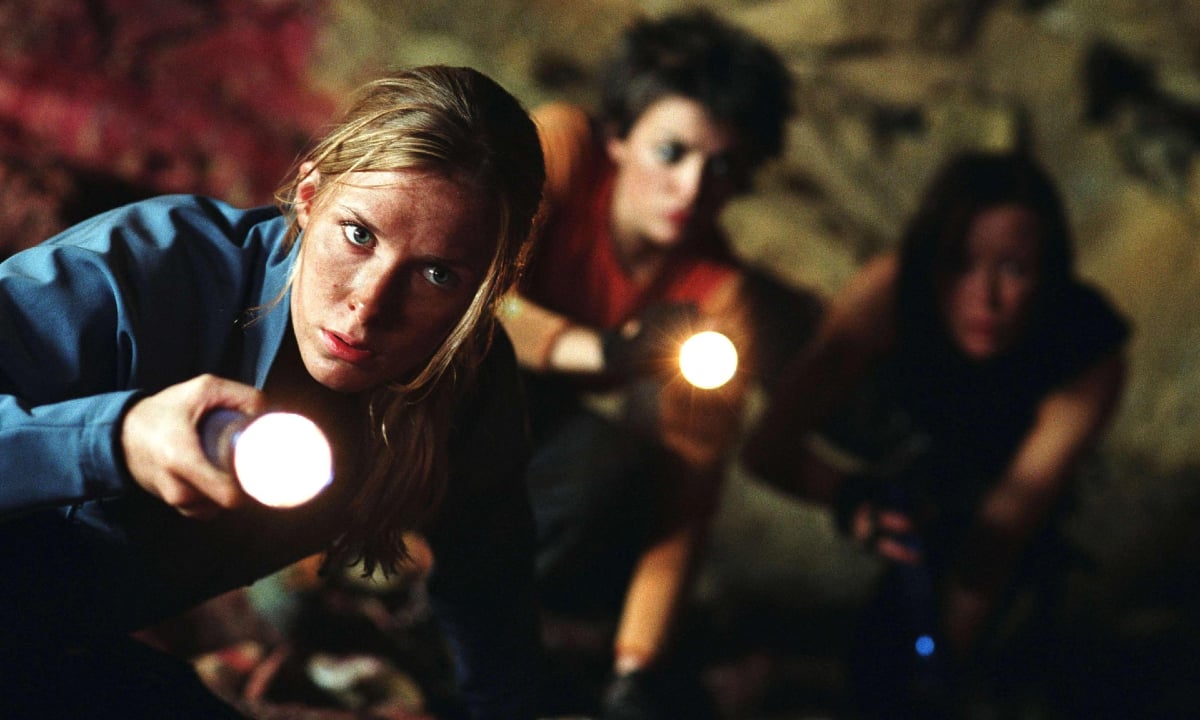 Three women explore a cave with flashlights in 'The Descent'