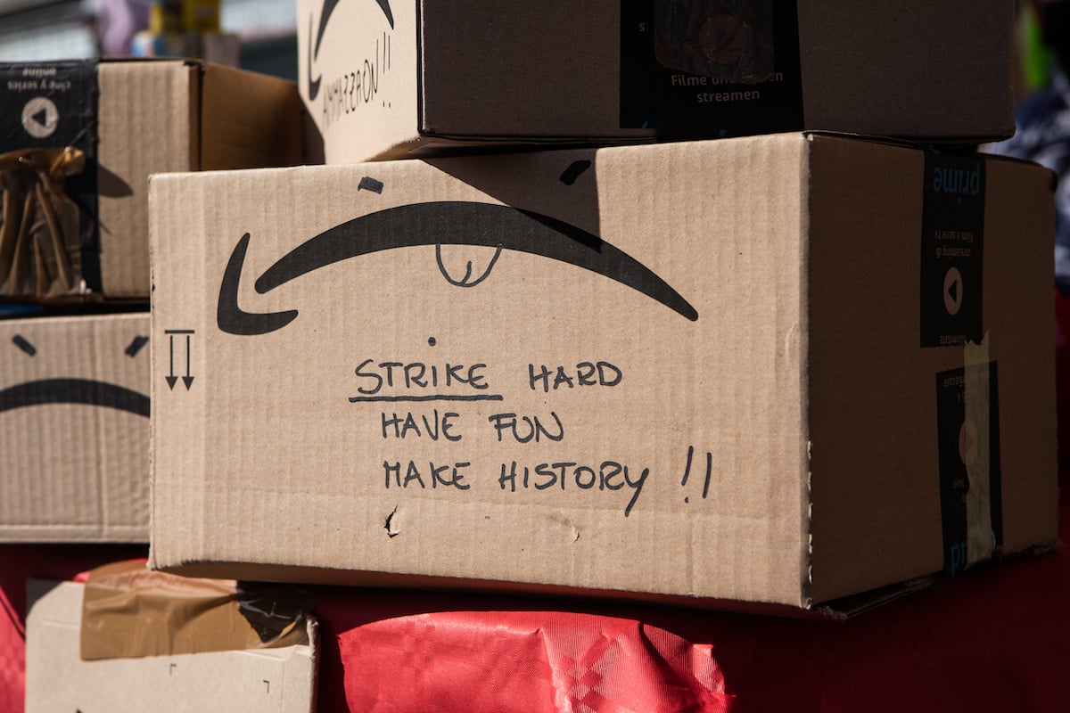 An Amazon package in a warehouse with a message written on the side in Sharpie: "Strike hard, have fun, make history"