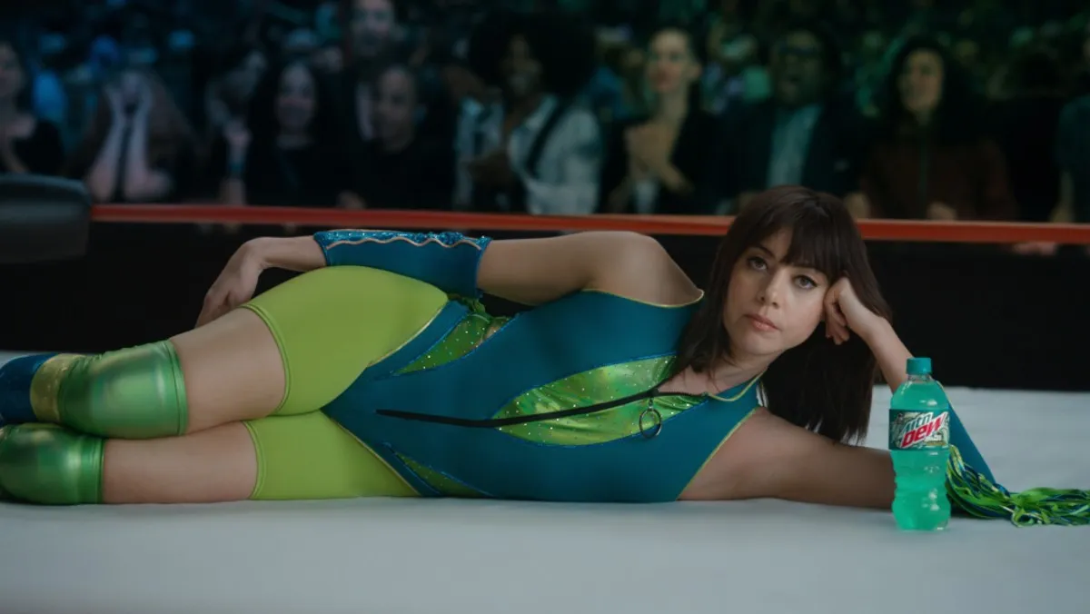 Aubrey Plaza dressed as a professional wrestler lies down next to a bottle of Mountain Dew for a Super Bowl commercial.